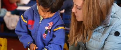 Een vrijwilliger tussen 18 en 25 jaar helpen een kind met een klasactiviteit tijdens haar vrijwilligerswerk kinderopvang in Peru. Als deel van de groepsreis kinderopvang in Peru, helpen Projects Abroad vrijwilligers tussen 18 en 25 in de klaslokalen.